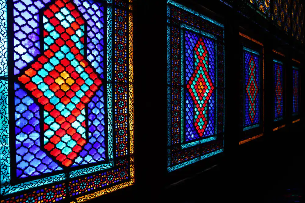 Backlit stained glass panel showing vibrant amber and cobalt blue hues