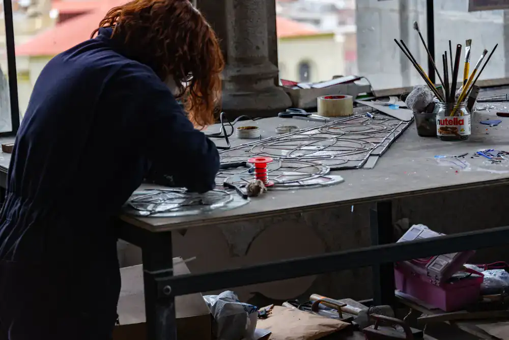 Artisan hands soldering lead joints on a glass panel